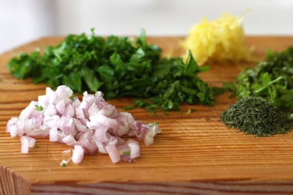 Xắt nhỏ hoặc băm nhỏ rau hẹ, mùi tây và các loại rau thơm khác. Sau đó, bạn cho rau vào một chiếc tô và đổ chút dầu oliu vào để trộn đều