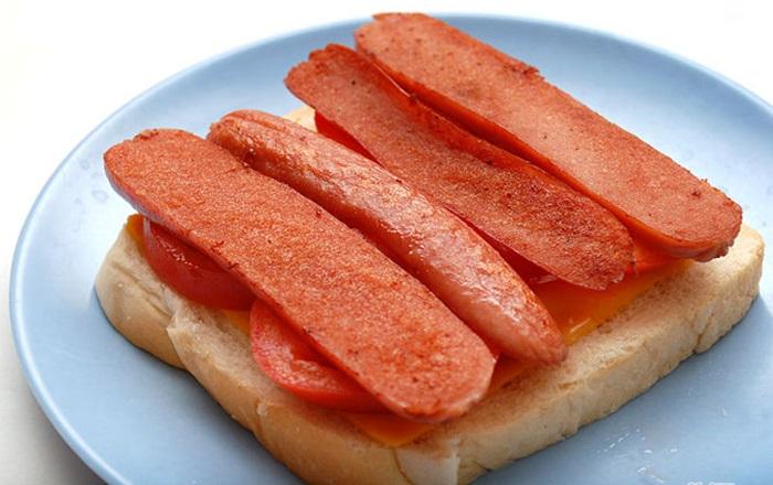 Tiếp đó, đặt thêm cà chua lên, xúc xích cắt làm đôi và đặt lên bánh mì như trong hình.