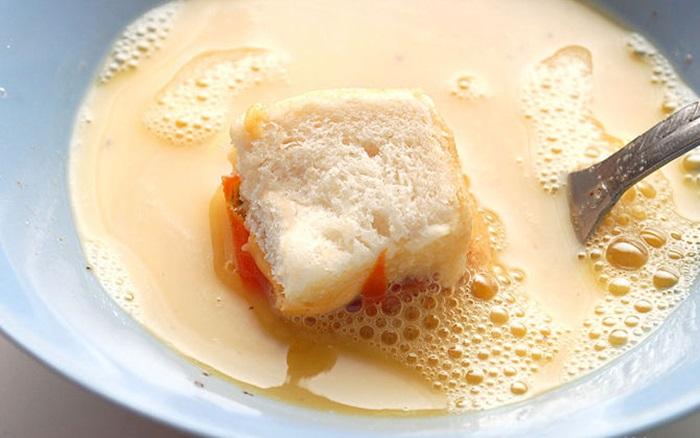 Nhúng những mẫu bánh mì nhỏ được cắt sẵn trước đó vào trứng, nhớ nhúng đều để trứng bao bọc hết mẫu bánh mì.